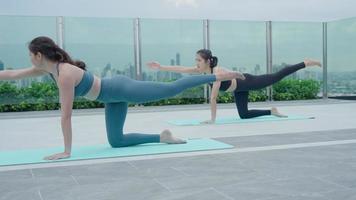 Due Asia sottile donna praticante yoga su il balcone di sua condominio. asiatico donna fare esercizi nel mattina. equilibrio, meditazione, rilassamento, calma, bene Salute, felice, relax, salutare stile di vita concetto video