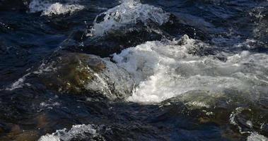 l'écume de la rivière s'écrasant contre le rocher au ralenti video