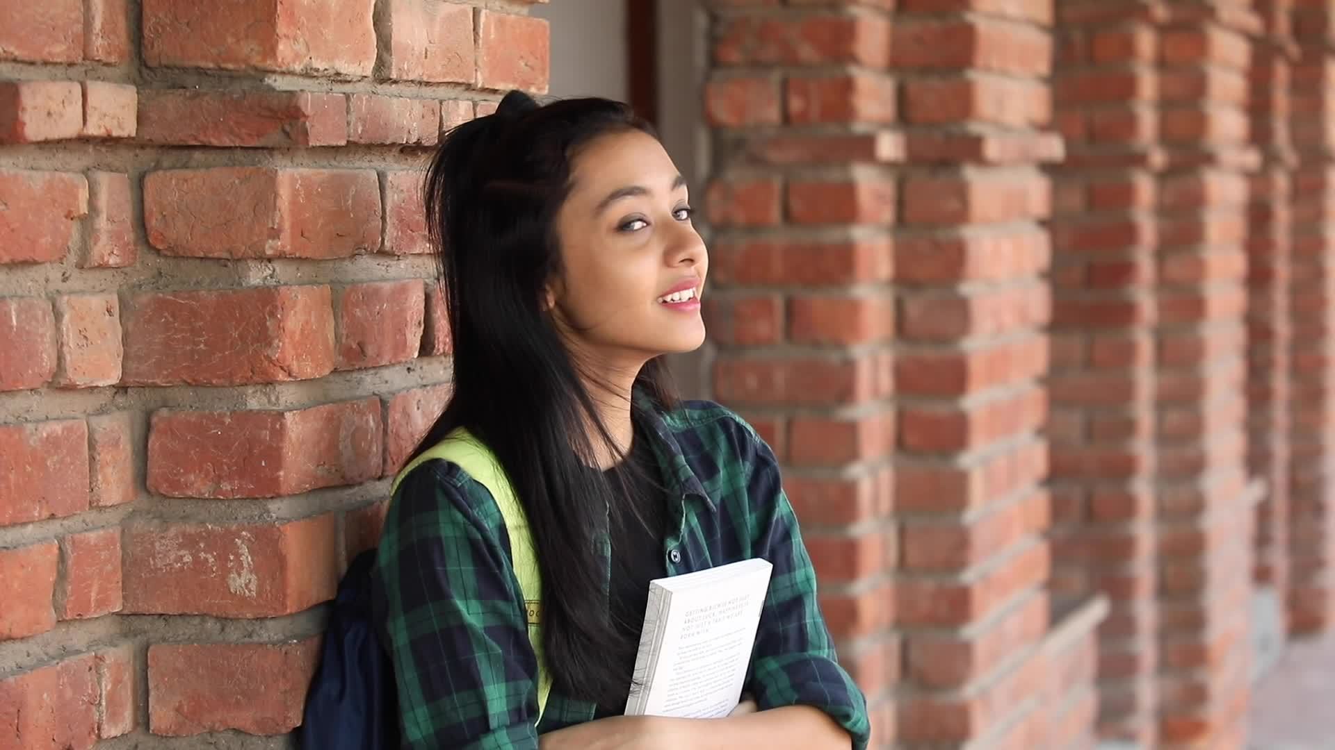 Video clip of a teenage Indian college girl carrying a backpack and holding  books. 16885781 Stock Video at Vecteezy