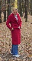 girl in red coat in autumn park. Shorts. slow motion video