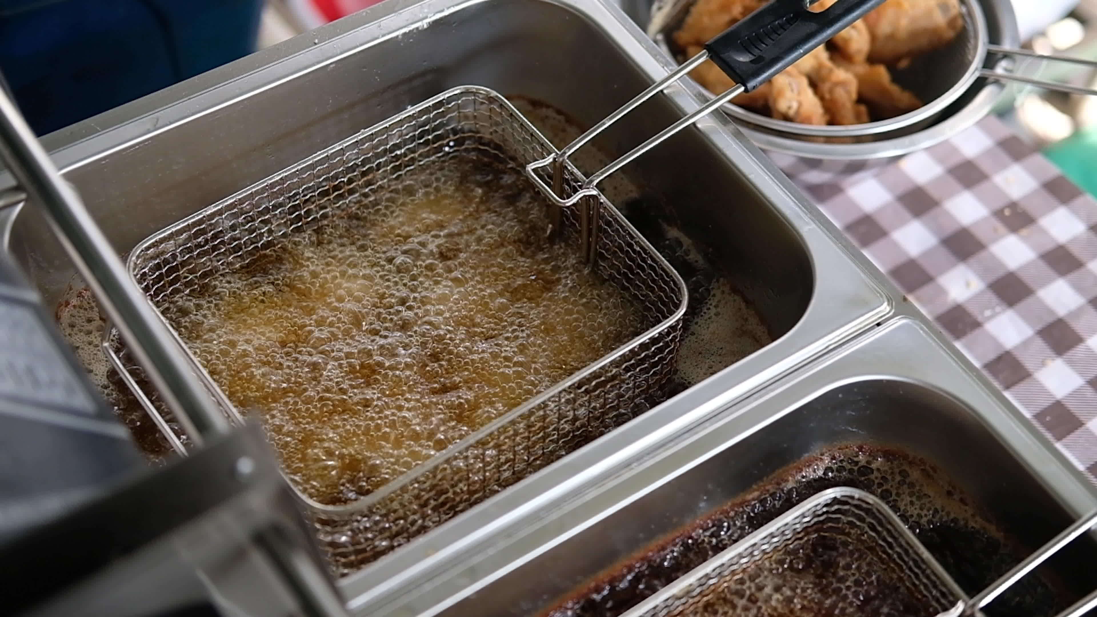 Huge amounts of oil boiling inside of the deep fryer. Cooking the food