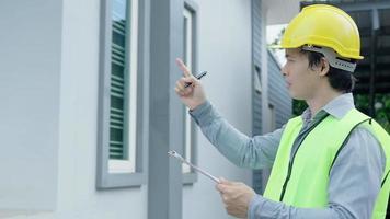 un inspecteur ou un ingénieur inspecte et inspecte un bâtiment ou une maison à l'aide d'une liste de contrôle. ingénieurs et architectes ou entrepreneur travaillent pour construire la maison avant de la remettre au propriétaire. video