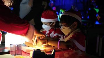 pais e filhos gostam de passar a véspera de natal juntos, fazendo enfeites de árvore de natal. linda garota brincando com luzes de natal video