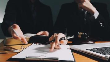 Business and lawyers discussing contract papers with brass scale on desk in office. Law, legal services, advice, justice and law concept picture with film grain effect video