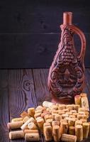 Clay bottle of wine and cork on a wooden table photo
