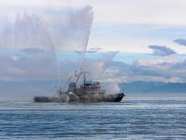 Floating tug boat is spraying jets of water photo