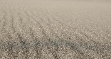 Textured wavy gray sand all over the frame. Selective focus photo