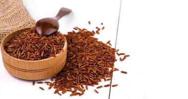 Dark rice, burlap and spoon in a wooden cup on a white dining table. photo