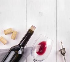 The glass bottle of wine with corks on white wooden table photo