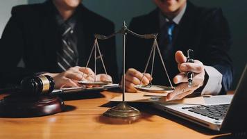 Business and lawyers discussing contract papers with brass scale on desk in office. Law, legal services, advice, justice and law concept picture with film grain effect video