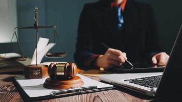 Business and lawyers discussing contract papers with brass scale on desk in office. Law, legal services, advice, justice and law concept picture with film grain effect video