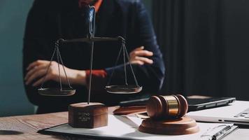 Business and lawyers discussing contract papers with brass scale on desk in office. Law, legal services, advice, justice and law concept picture with film grain effect video