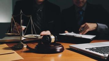 Business and lawyers discussing contract papers with brass scale on desk in office. Law, legal services, advice, justice and law concept picture with film grain effect video