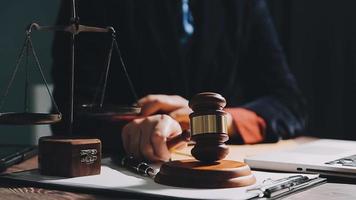 Business and lawyers discussing contract papers with brass scale on desk in office. Law, legal services, advice, justice and law concept picture with film grain effect video