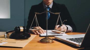 Business and lawyers discussing contract papers with brass scale on desk in office. Law, legal services, advice, justice and law concept picture with film grain effect video