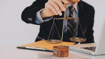 Business and lawyers discussing contract papers with brass scale on desk in office. Law, legal services, advice, justice and law concept picture with film grain effect video