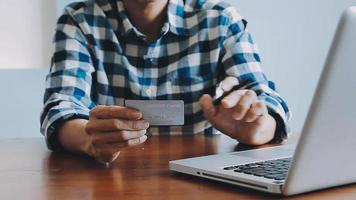 mãos segurando um cartão de crédito e usando o laptop. compras online video