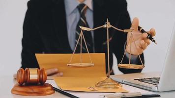 Business and lawyers discussing contract papers with brass scale on desk in office. Law, legal services, advice, justice and law concept picture with film grain effect video