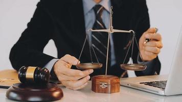 Business and lawyers discussing contract papers with brass scale on desk in office. Law, legal services, advice, justice and law concept picture with film grain effect video