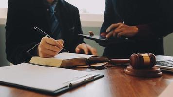 Business and lawyers discussing contract papers with brass scale on desk in office. Law, legal services, advice, justice and law concept picture with film grain effect video