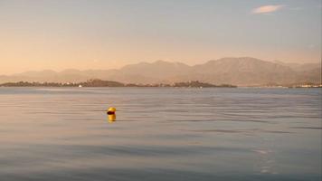 filmmateriaal, zonsondergang over- een baai in de Egeïsch zee, kalmte zee, 4k video, selectief focus Aan een geel boei. idee voor achtergrond of behang video