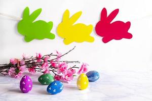 Colorful eggs with handmade bunny easter garland on netural background. photo