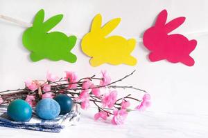 Colorful eggs with willow and handmade bunny easter garland on netural background. photo