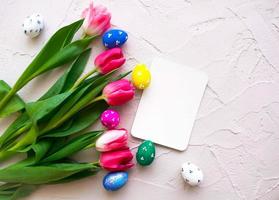 Happy ester. color eggs with tulips on grey background top view photo