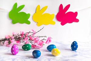 Colorful eggs with willow and handmade bunny easter garland on netural background. photo