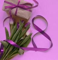 hermosos tulipanes de primavera, caja de regalo y cinta en forma de ocho sobre fondo rosa. concepto de día de san valentín, día de la mujer ocho de marzo, día de la madre. foto