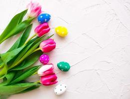 Happy ester. color eggs with tulips on grey background top view photo