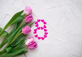 hermosos tulipanes de primavera y corazones en forma de ocho sobre fondo de piedra gris. concepto de día de san valentín, día de la mujer ocho de marzo, día de la madre. espacio para texto, foto