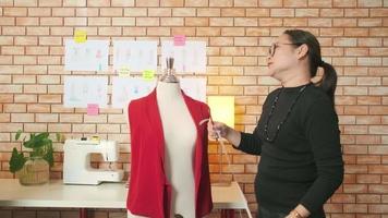 une créatrice de mode asiatique d'âge moyen travaille en studio en mesurant des formes de marionnettes, en réfléchissant et en pensant à des idées, une collection de conception de vêtements d'imagination, une boutique professionnelle tailleur PME entrepreneur. video