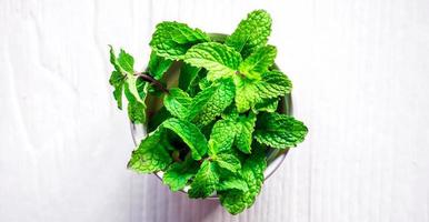 Top view of Mint leaf or Fresh mint herbs in a white bowl on white background photo