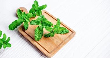 Mint leaf or Fresh mint on a wooden chopping board on white background