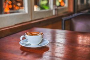 A cup of coffee on wooden table in coffee shop photo