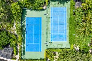 Amazing birds eye view of a tennis court surrounded by palm trees. Aerial tennis fields, outdoor sport and recreation concept