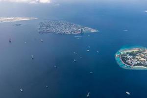 Aerial view of Maldives islands and atolls. Maldives tourism and travel background. Amazing blue sea, coral reef and atoll drone view. Beautiful nature landscape, seascape, exotic destination photo