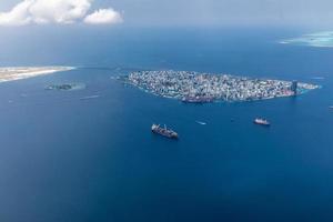 Aerial view of Maldives islands and atolls. Maldives tourism and travel background. Amazing blue sea, coral reef and atoll drone view. Beautiful nature landscape, seascape, exotic destination photo