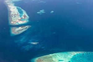 Aerial view of Maldives islands and atolls. Maldives tourism and travel background. Amazing blue sea, coral reef and atoll drone view. Beautiful nature landscape, seascape, exotic destination photo