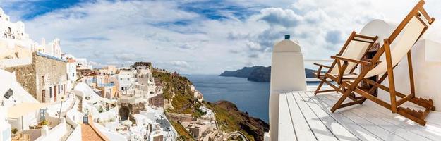 increíble paisaje panorámico, vacaciones de viaje de lujo. ciudad de oia en la isla de santorini, grecia. un par de sillas en la caldera, mar Egeo. romántico destino de amor de luna de miel. panorama pintoresco foto