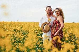 pareja embarazada por un campo de flores amarillas foto