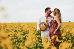 Pregnant couple by a field of yellow flowers photo