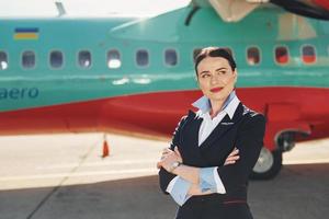 azafata. tripulación de trabajadores del aeropuerto y del avión con ropa formal de pie juntos al aire libre foto