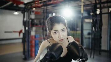 foto pov de uma jovem determinada em luvas esportivas vermelhas praticando pucnhes de boxe e olhando para a câmera em pé no ringue video