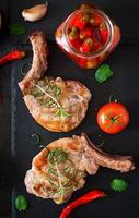 Grilled juicy steak on the bone with vegetables on a dark background. Top view photo