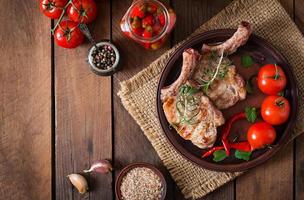 Grilled juicy steak on the bone with vegetables on a wooden background. Top view photo