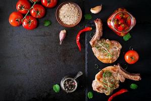 Grilled juicy steak on the bone with vegetables on a dark background. Top view photo