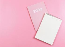 endecha plana de cuaderno de papel en blanco en el diario rosa 2023 sobre fondo rosa. foto