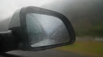 Blick aus dem Inneren eines fahrenden Autos entlang der Autobahn auf den Seitenspiegel bei Regen. das Konzept von Fahrzeugen und Fahrern. keine Leute. video